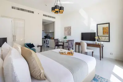a bedroom with a white bed and a dining room at Frank Porter - Damac Ghalia in Dubai