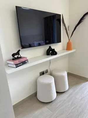 a living room with two stools and a television on a wall at Modern Studio Near Burj Khalifa in Dubai