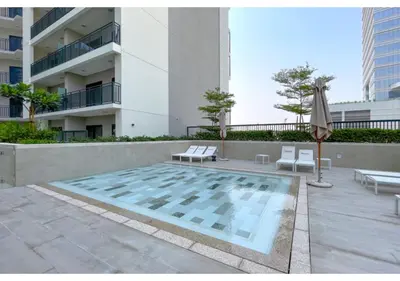 a swimming pool with two chairs and an umbrella and a building at Keyrock Living - Lakeview Luxury with Pool Access in Dubai