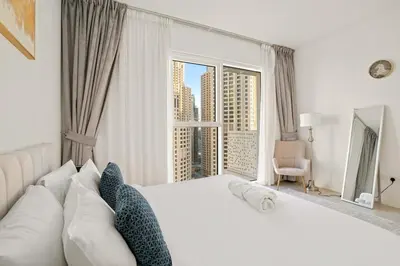 a bedroom with a large white bed with a large window at Modern 1BR Apartment Steps from Beach and Dubai Nightlife in Dubai