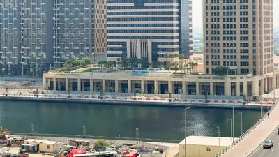 a large building next to a river with tall buildings at Keyrock - Zada Tower, Business Bay Lake-View Apartment in Dubai