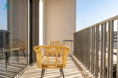 a wicker chair sitting on a balcony with a table at Blue Breeze - Stylish Studio Retreat in MBR City in Dubai