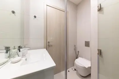 a white bathroom with a toilet and a sink at Luma Studio in Jumeirah Village Circle in Dubai