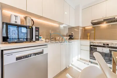 a kitchen with white cabinets and a microwave at Balcony Overlooking the Swimming Pool, Just Minutes from the Park, Town Square Safi 1A, Al Yelayiss 2 by Deluxe Holiday Homes in Dubai