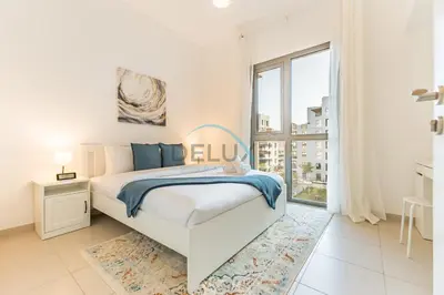 a white bedroom with a bed and a large window at Balcony Overlooking the Swimming Pool, Just Minutes from the Park, Town Square Safi 1A, Al Yelayiss 2 by Deluxe Holiday Homes in Dubai