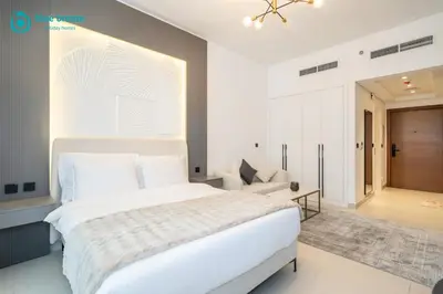 a bedroom with a large white bed and a living room at Blue Breeze - Trendy Studio with Balcony & Stylish Interiors in Dubai