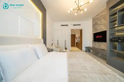 a bedroom with a large white bed and a tv at Blue Breeze - Trendy Studio with Balcony & Stylish Interiors in Dubai