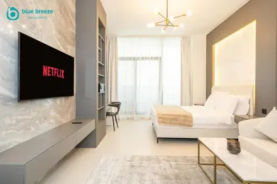 a bedroom with a bed and a tv on a wall at Blue Breeze - Trendy Studio with Balcony & Stylish Interiors in Dubai