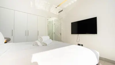 a white bedroom with a bed with a flat screen tv at Lavish Sidra 3 Villa, 4BR plus M,Private Pool BBQ in Dubai