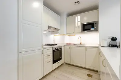 a white kitchen with white cabinets and a sink at Livbnb-Stylish 1B with Spacious Balcony in JVC in Dubai