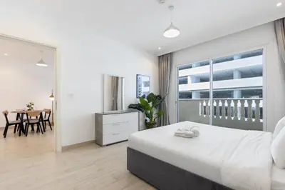 a bedroom with a large bed and a dining room at Livbnb-Stylish 1B with Spacious Balcony in JVC in Dubai