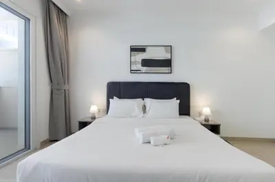 a bedroom with a white bed with two towels on it at Livbnb-Stylish 1B with Spacious Balcony in JVC in Dubai