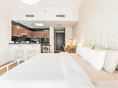 a bedroom with a white bed and a kitchen at Special Rate - Luxurious Studio - Golf View in Dubai