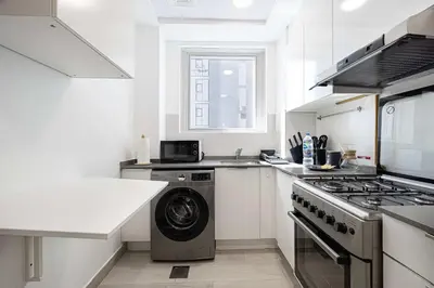 a white kitchen with a washing machine in it at Stylish 1-Bedroom Apartment with Premium Amenities in Dubai