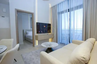 a white living room with a couch and a table at Standard 2BHK located in Azizi riviera 46 in Dubai