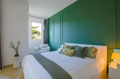 a bedroom with a large bed with green walls at Spacious studio in a green oasis in Dubai