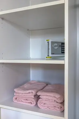 a closet with pink towels and a microwave at Spacious studio in a green oasis in Dubai