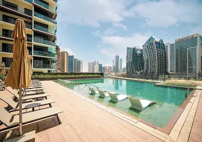 a swimming pool with lounge chairs and an umbrella at Chic Studio with Top Amenities in Dubai