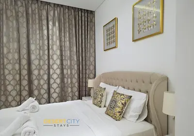 a bedroom with a bed with white sheets and pillows at Elegant 2BR in Dubai Hills Estate Hosted by Desert City Stays in Dubai