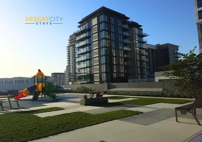 a playground in a park with a large building at Elegant 2BR in Dubai Hills Estate Hosted by Desert City Stays in Dubai