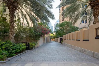 a cobblestone alley with palm trees and buildings at Frank Porter - Yansoon 5 in Dubai