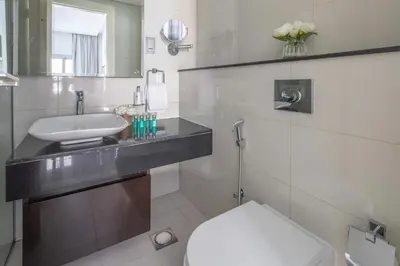 a white bathroom with a sink and a toilet at Frank Porter - Damac Majestine in Dubai