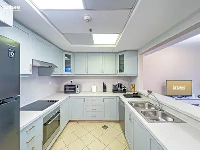 a kitchen with white cabinets and a sink at bnbmehomes - Golf Tower 1 in Dubai