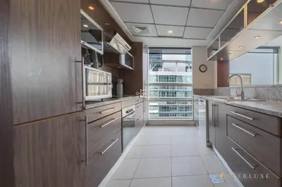 a kitchen with wooden cabinets and a large window at Beautiful & Spacious 3 Bedroom Wmaids In Marina in Dubai