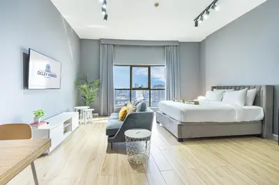 a bedroom with a bed and a living room with a couch at Stylish & Compact Home in the Heart of the JVC in Dubai