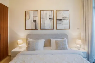 a bedroom with a bed with three pictures on the wall at 13 - Stylish Dorra Bay Family Apartment - Canal View & Pool Access in Dubai