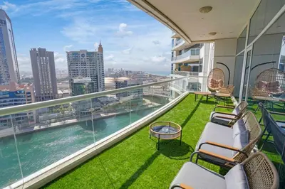 a balcony with chairs and a view of the water at 13 - Stylish Dorra Bay Family Apartment - Canal View & Pool Access in Dubai