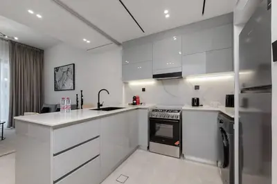 a white kitchen with a sink and a stove at Cozy 1BR apartment Binghatti Canal Business Bay in Dubai
