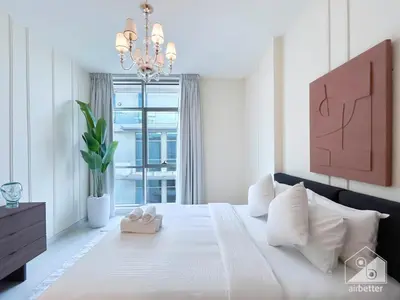 a white bedroom with a large bed with a chandelier at Your Perfect Meydan Getaway 1B Polo Residence C3 in Dubai