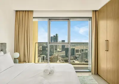a bedroom with a white bed and a large window at Burj Royale Dubai Downtown in Dubai