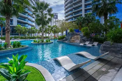 a swimming pool with lounge chairs in a resort at Prime 1BR Location Minutes to Burj Dubai Mall by Vibel in Dubai