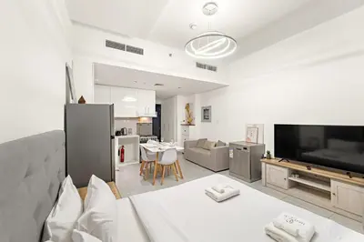 a living room with a large television and a kitchen at Studio Dubai, Cozy Luxury Stay Near Downtown Dining Shopping & Leisure in Dubai