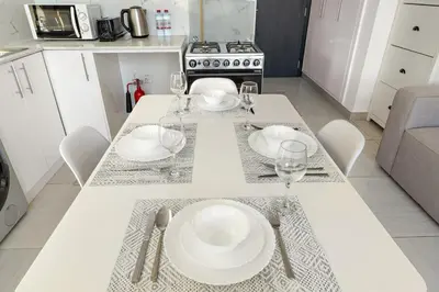 a kitchen with a table with plates and wine glasses at Studio Dubai, Cozy Luxury Stay Near Downtown Dining Shopping & Leisure in Dubai