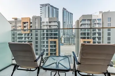 a balcony with two chairs and a view of a city at City View Studio Minutes Drive to Burj Khalifa, Azizi Riviera 43, Al Merkadh by Deluxe Holiday Homes in Dubai