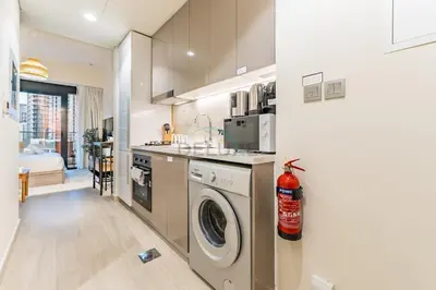 a kitchen with a washer and dryer in a room at City View Studio Minutes Drive to Burj Khalifa, Azizi Riviera 43, Al Merkadh by Deluxe Holiday Homes in Dubai
