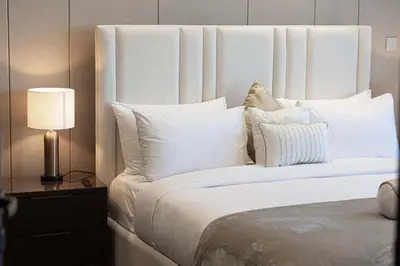 a bed with white pillows and a lamp on a table at Modern 1-Bedroom Apartment with Stunning Burj Khalifa and city Views in Dubai