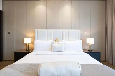 a bedroom with a large white bed with two lamps at Modern 1-Bedroom Apartment with Stunning Burj Khalifa and city Views in Dubai