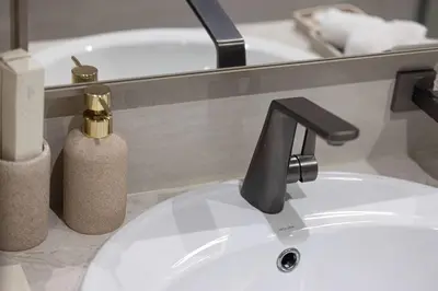a bathroom sink with a black faucet next to a bath tub at Modern 1-Bedroom Apartment with Stunning Burj Khalifa and city Views in Dubai