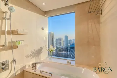 a bathroom with a bath tub and a large window at The Captivating in Dubai