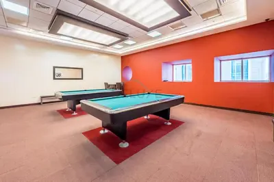 two pool tables in a room with orange walls at Renovated Unit with Skyscraper Views, Close to JBR Beach, Elite Residence, Dubai Marina by Deluxe Holiday Homes in Dubai