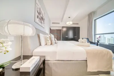 a bedroom with a large white bed and a window at High Floor 2BR With a View of the Dubai Marina Canal Steps Away From the Beach , Shams 1, JBR by Deluxe Holiday Homes in Dubai