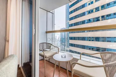 a balcony with a table and chairs and a window at Refurbished 1BR High-Floor Unit with Partial City & Sea Views, Walking Distance to the Beach, Elite Residence, Dubai Marina by Deluxe Holiday Homes in Dubai