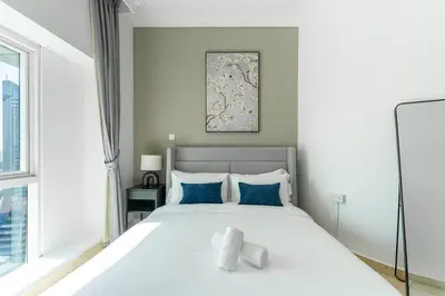 a bedroom with a large white bed with blue pillows at HAVN - 2-Storey Apartment with Dubai Marina Views in Dubai