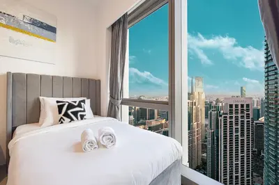 a bedroom with a large window with a view of a city at Stay in the #1 Burj & Fountain View 4BR Apartment in Dubai