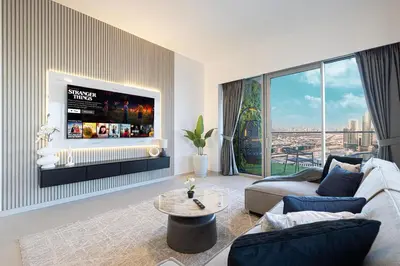 a living room with a couch and a tv on a wall at Stay in the #1 Burj & Fountain View 4BR Apartment in Dubai