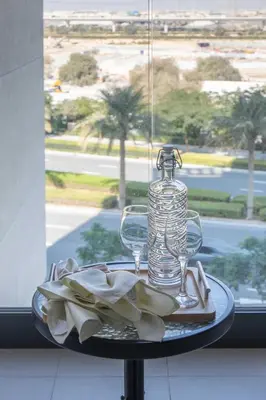 a table with a glass bottle and a plate of food at Frank Porter - Prive Residence in Dubai